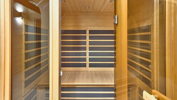 A sauna with wooden walls and a glass door.