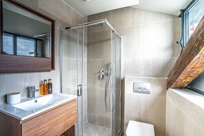 A modern bathroom with a glass shower enclosure, a wooden vanity, and a large mirror.