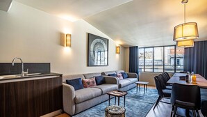 A modern living room with a sofa, a dining table, and a kitchen area.