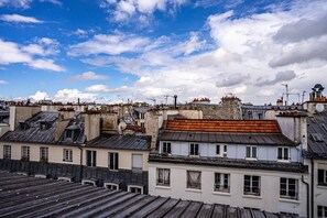 A view of a densely packed urban area with multiple buildings, some with visible rooftops and chimneys, under a partly cloudy sky.
