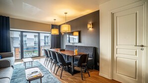 Ein modernes Hotelzimmer mit Essbereich, einer Couch und einem großen Fenster mit Blick auf die Stadt.