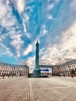 A large open square with a tall monument in the center, surrounded by classical architecture.