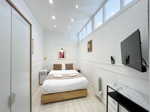 A modern bedroom with a bed, a TV, and a radiator. - UrbanFlat 68 - Cosy Rolling Stones Apartment Paris (París)
