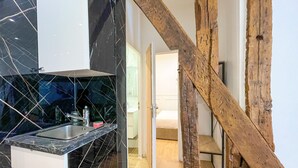 A modern kitchen with a black marble backsplash, a white cabinet, and a wooden beam structure.