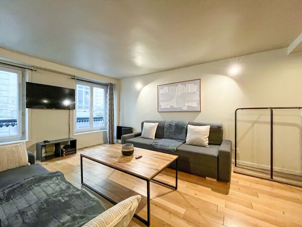 Una sala de estar moderna con sofá, mesa de centro y televisor.