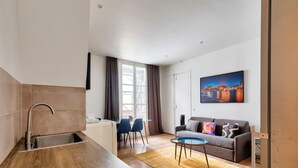Eine moderne Küche mit Spüle und Essbereich, ein Sofa mit Kissen sowie ein Gemälde an der Wand.