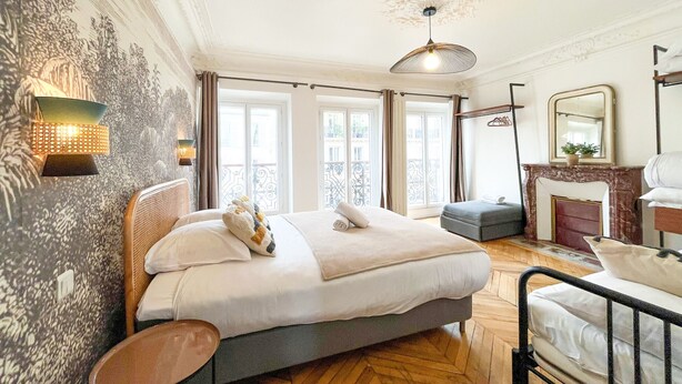 Een slaapkamer met een groot bed, een klein tafeltje, een spiegel en een open haard.