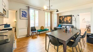 Een moderne woonkamer met een eethoek, houten vloeren en grote ramen.