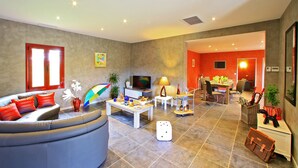 Een moderne woonkamer met een bank, televisie en een eethoek.