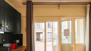 Ein Zimmer mit einem dunklen Holzschrank, einem roten Sessel und einer Tür, die auf einen Balkon führt.
