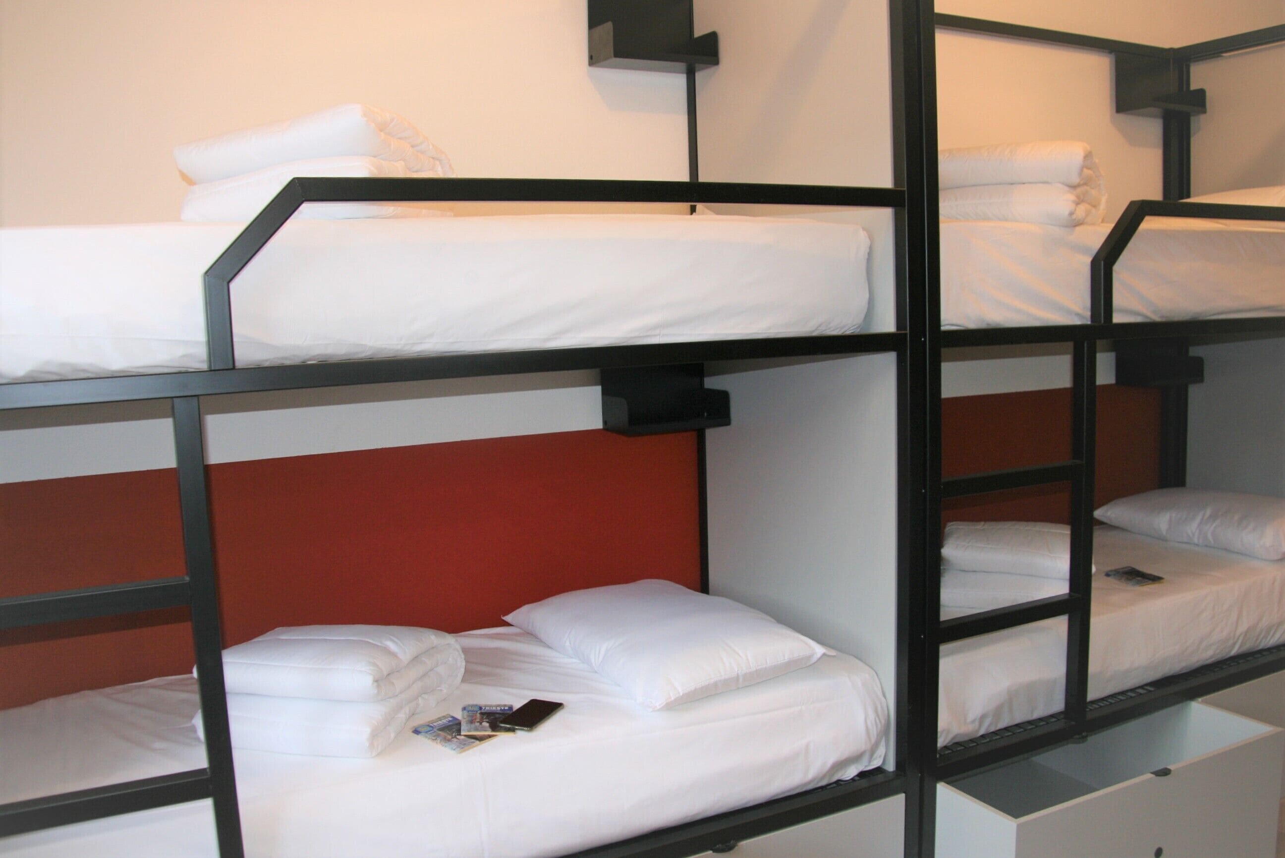 A bunk bed room with white bedding and a red headboard.