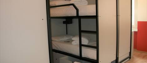 Uma cama de solteiro com roupa de cama branca e uma toalha pendurada na cama inferior.