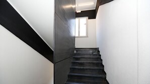 A modern staircase with a black and white color scheme, leading to a room with a window. - Hotello Hostel (Trieste)