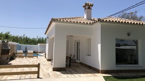 A single-story house with a tiled roof, a chimney, a swimming pool, and a patio area. - Rocamar House (Barbate)