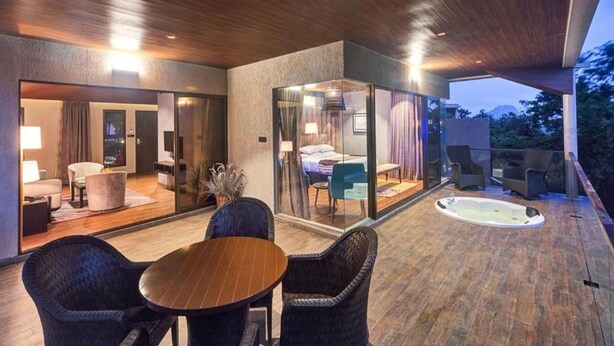 Un espacio exterior moderno con terraza de madera, un jacuzzi y un dormitorio con paredes de cristal.