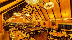 Un restaurante espacioso con techos altos y vigas de madera, que cuenta con varias mesas y cabinas para comer.