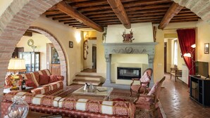 Una sala de estar acogedora con chimenea, muebles tapizados en rojo y un arco de ladrillo.