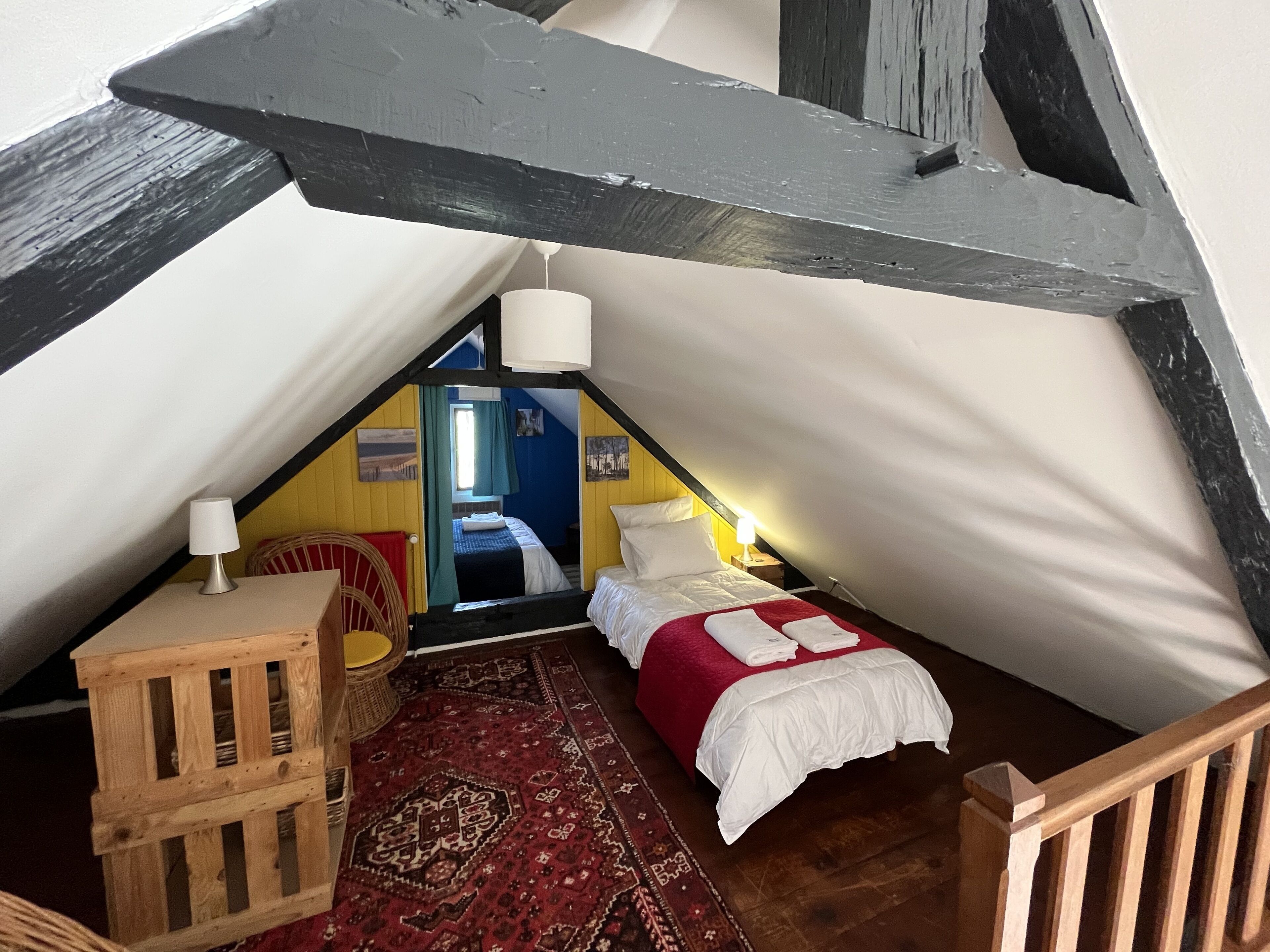 A cozy attic bedroom with a bed, a small table, and a chair.