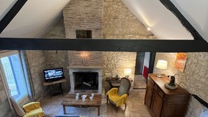 Een loft-achtige kamer met een open haard, een eettafel en een televisie.