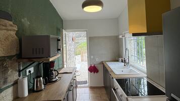 Eine Küche mit Steinwand, Kaffeemaschine, Mikrowelle und Spüle.