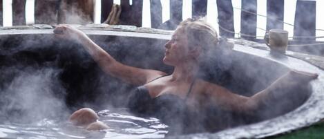 A person relaxing in a hot tub with steam rising around them.