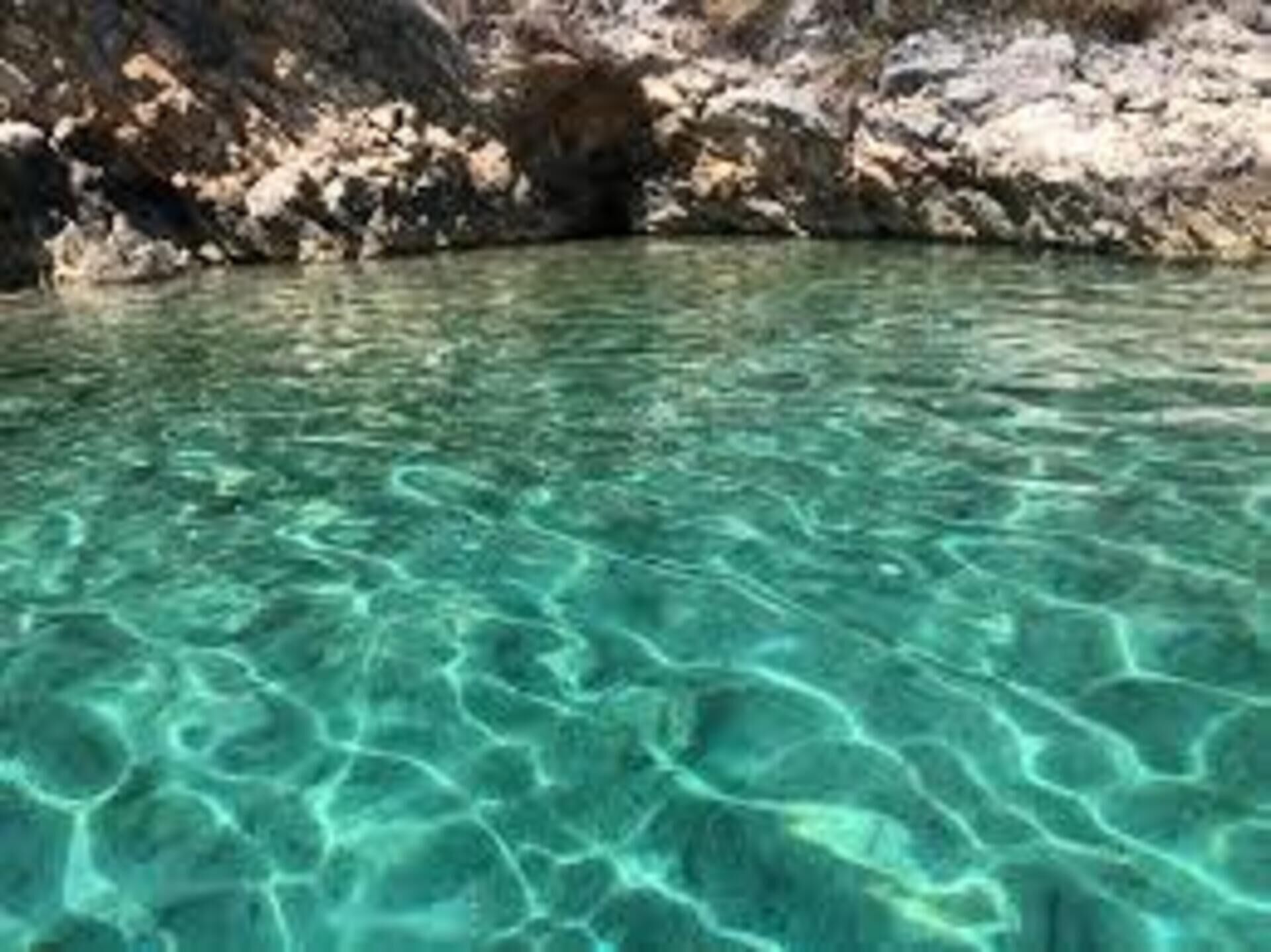 Una extensión de agua clara y poco profunda con terreno rocoso al fondo.
