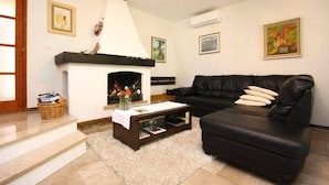 A living room with a fireplace, a black leather sofa, and a coffee table. - Captivating 3-bedroom Villa in Kanica (Rogoznica)