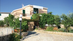 A two-story building with a balcony, surrounded by greenery and a stone pathway. - Captivating 3-bedroom Villa in Kanica (Rogoznica)