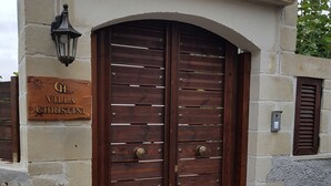 Ein Villaeneingang mit einer zweiflügeligen Holztür, einem Schild mit der Aufschrift "Villa Christini" und einer Wandleuchte.