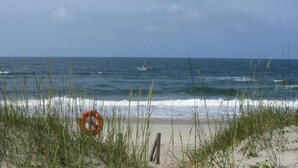 A beach with waves, a lifebuoy, and a boat in the distance. - Sandcastle by the Sea - 3Bedroom, 2 Bath/Sleeps 6 - South Beach - Oceanside  (Bald Head Island)