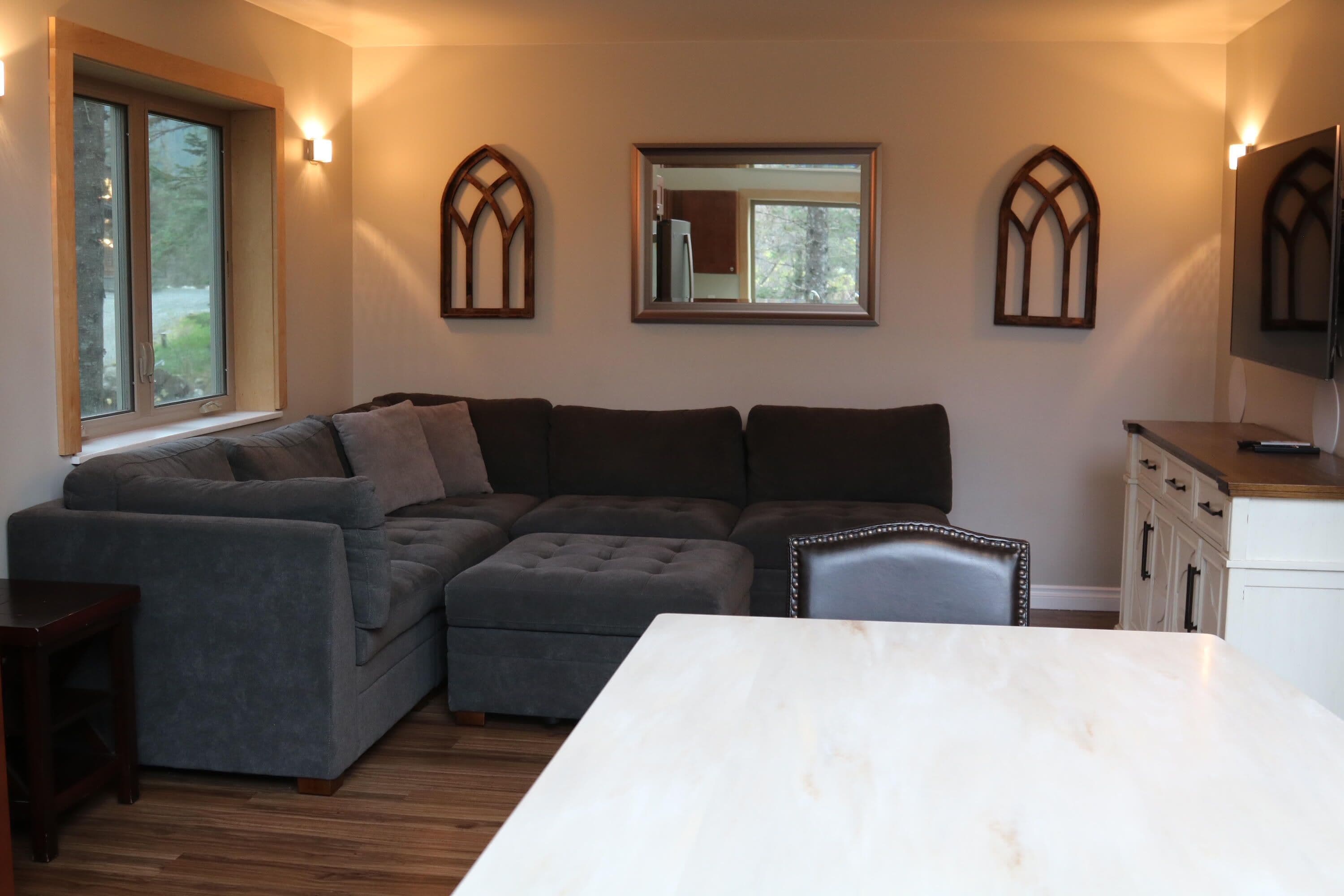 Ein modernes Wohnzimmer mit Ecksofa, Esstisch und Küchenbereich inklusive Schränke und Kühlschrank.