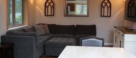 Ein modernes Wohnzimmer mit Ecksofa, Esstisch und Küchenbereich inklusive Schränke und Kühlschrank.