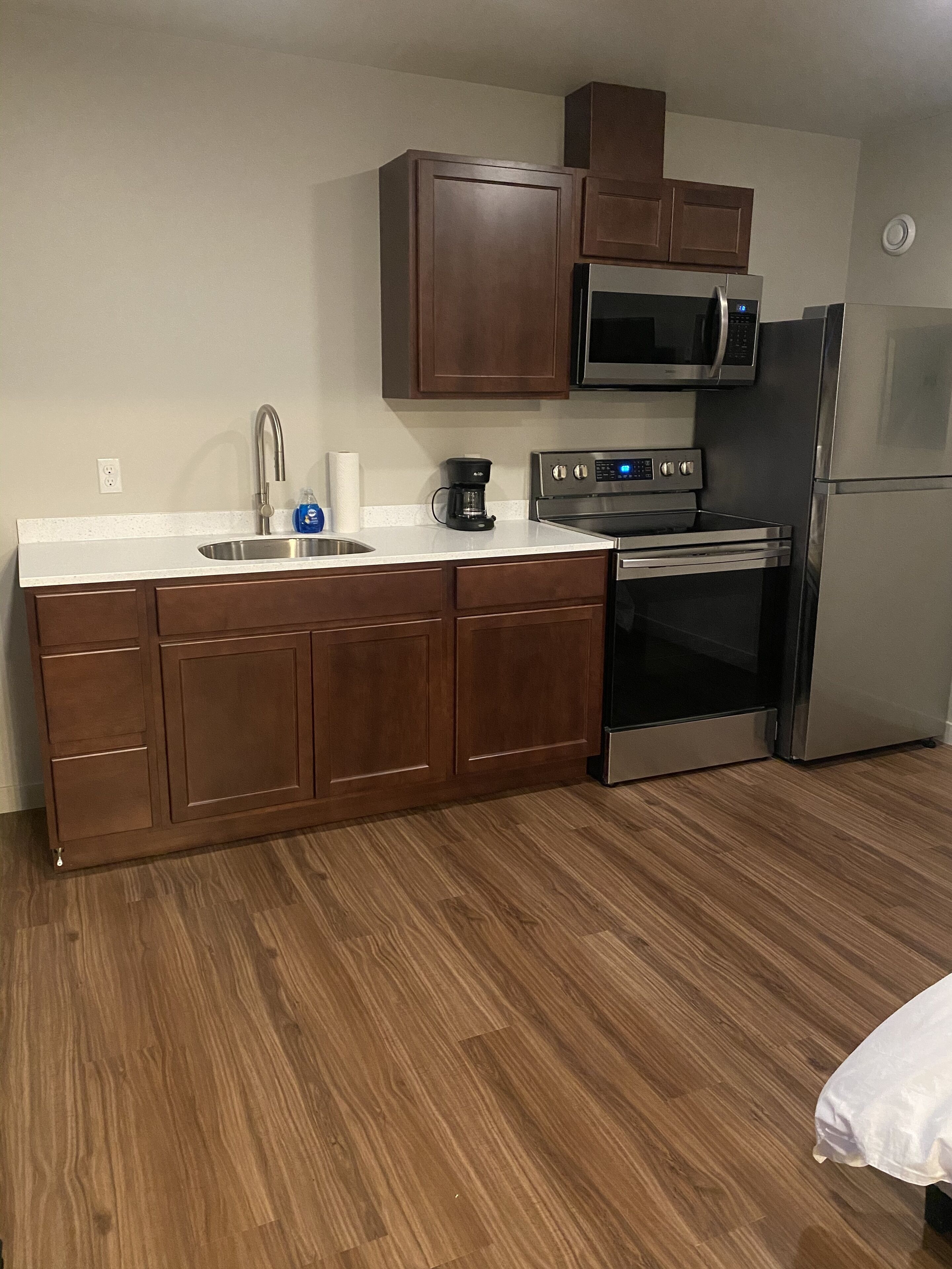 A compact kitchen with a stainless steel refrigerator, a microwave, and an oven.