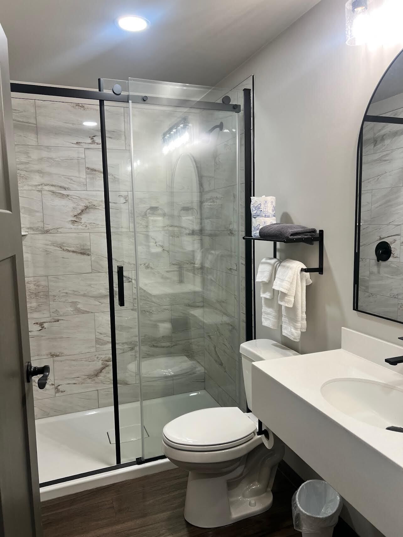 Un baño moderno con ducha de vidrio, inodoro blanco y tocador con espejo.