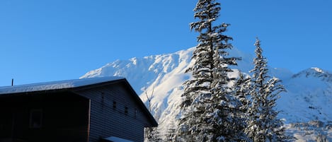 Une cabane en bois, avec une montagne enneigée en arrière-plan.