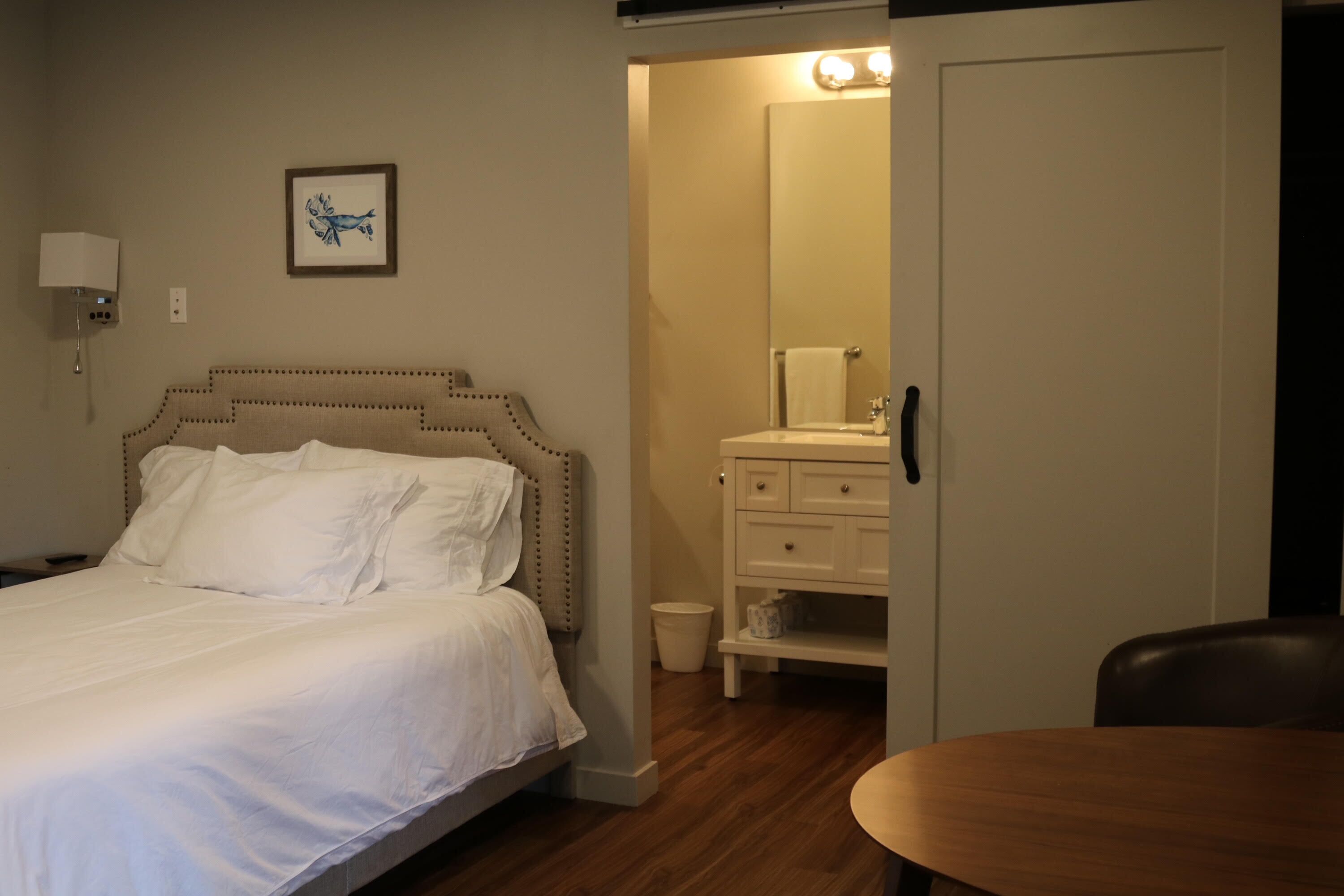 A bedroom with a bed, a bedside lamp, a nightstand, a dresser, and a mirror.
