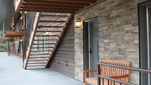 Un bâtiment doté d’une façade en pierre, d’un escalier en bois et d’un banc.