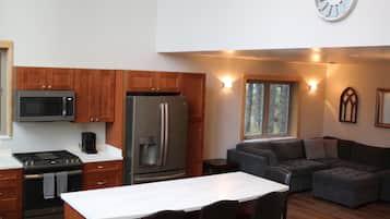 A modern kitchen with a microwave, stove, refrigerator, and a dining area with a table and chairs.