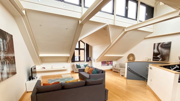 Un appartement-loft spacieux avec de hauts plafonds, une mezzanine et un coin cuisine.