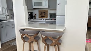 A modern kitchen with grey cabinets, a white countertop, and two wooden stools. - Stand alone villa  (Venice)