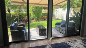 A patio area with wicker furniture, a glass table, and a blue and white patterned rug. - Stand alone villa  (Venice)