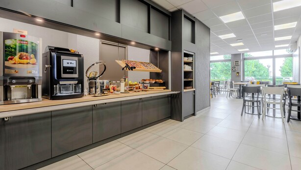 A modern cafe with a counter, coffee machines, and seating area. - B&B HOTEL Cambrai (Proville)