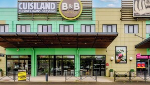 A hotel with a green facade, a B&B sign, and a sign for CUISILAND Cuisines-Bains-Dressing. - B&B HOTEL Cambrai (Proville)