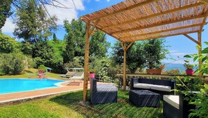 Ein Garten mit Schwimmbad, Gartenmöbeln und einer Pergola.