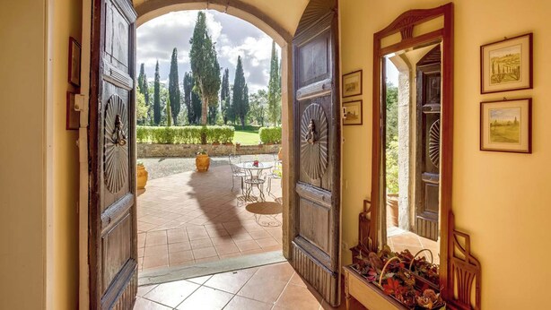 A hallway with a view of a garden, a dining area, and a mirror reflecting the garden. - Villa Il Giardino with Private Swimming Pool, Garden, Ideal for Weddings (Radicofani (SI))