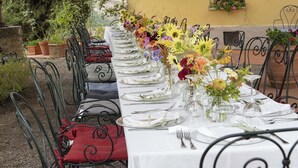 A long dining table set outdoors with metal chairs, white tablecloth, and floral centerpieces. - Villa Il Giardino with Private Swimming Pool, Garden, Ideal for Weddings (Radicofani (SI))