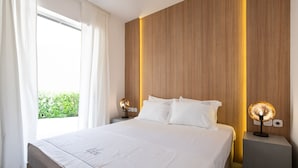 A neatly made bed with white linens, a wooden headboard, and two bedside lamps. - Elisa Seaside Luxury Suite Private hot Tub, Beach (Loutraki-Agioi Theodoroi)