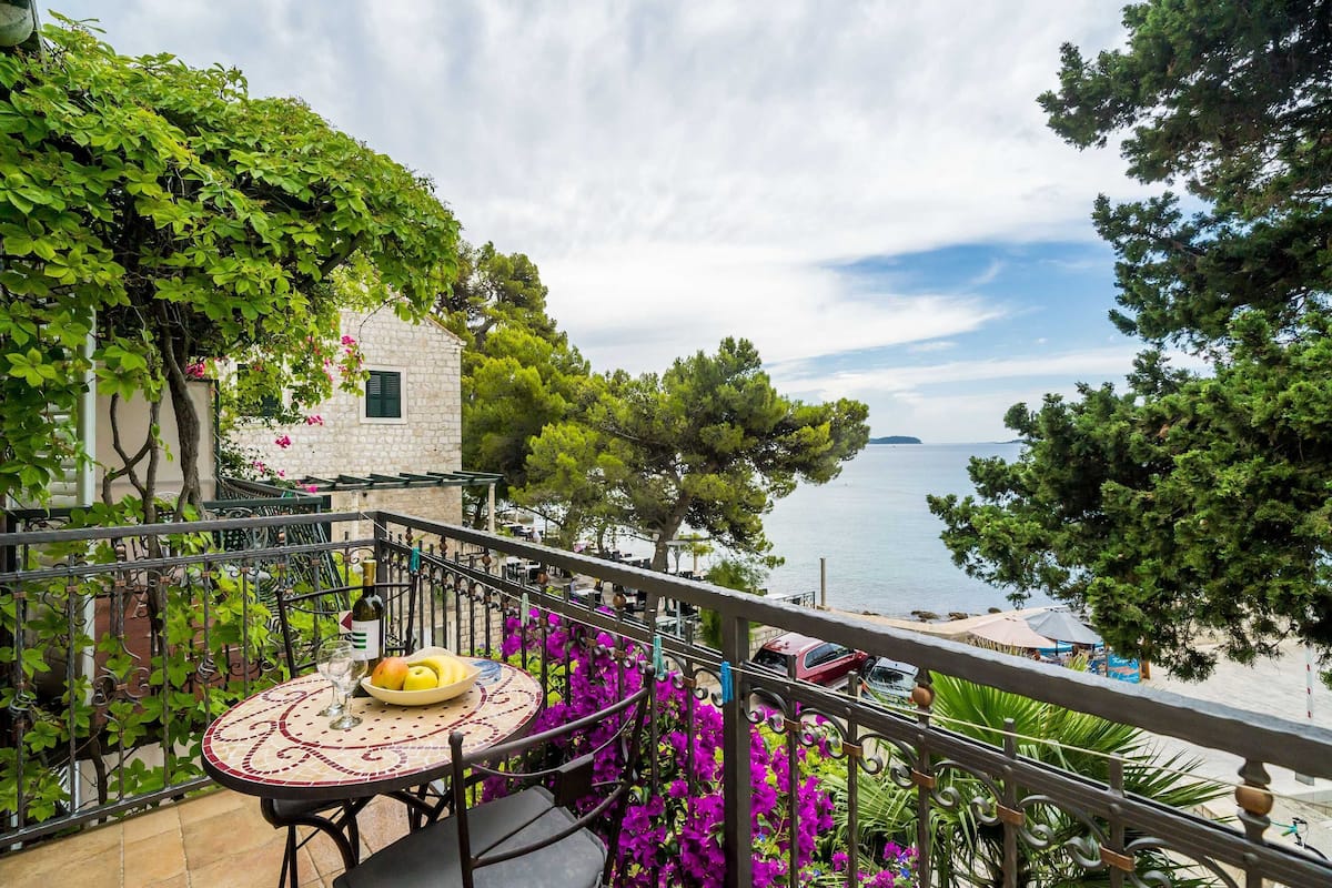 A balcony with a table, chairs, and a view of the sea.