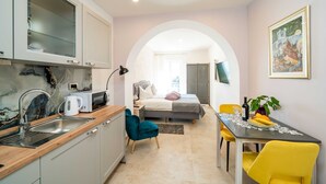 A compact hotel room with a kitchenette, a bed with a view, a dining area, and a living space. - Apartments Villa Palma (Zupa dubrovacka)