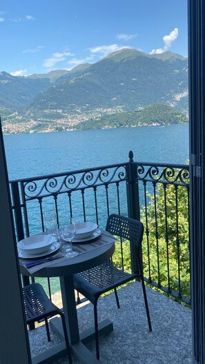 Een balkon met een tafel voor twee, met uitzicht op een meer en bergen op de achtergrond.